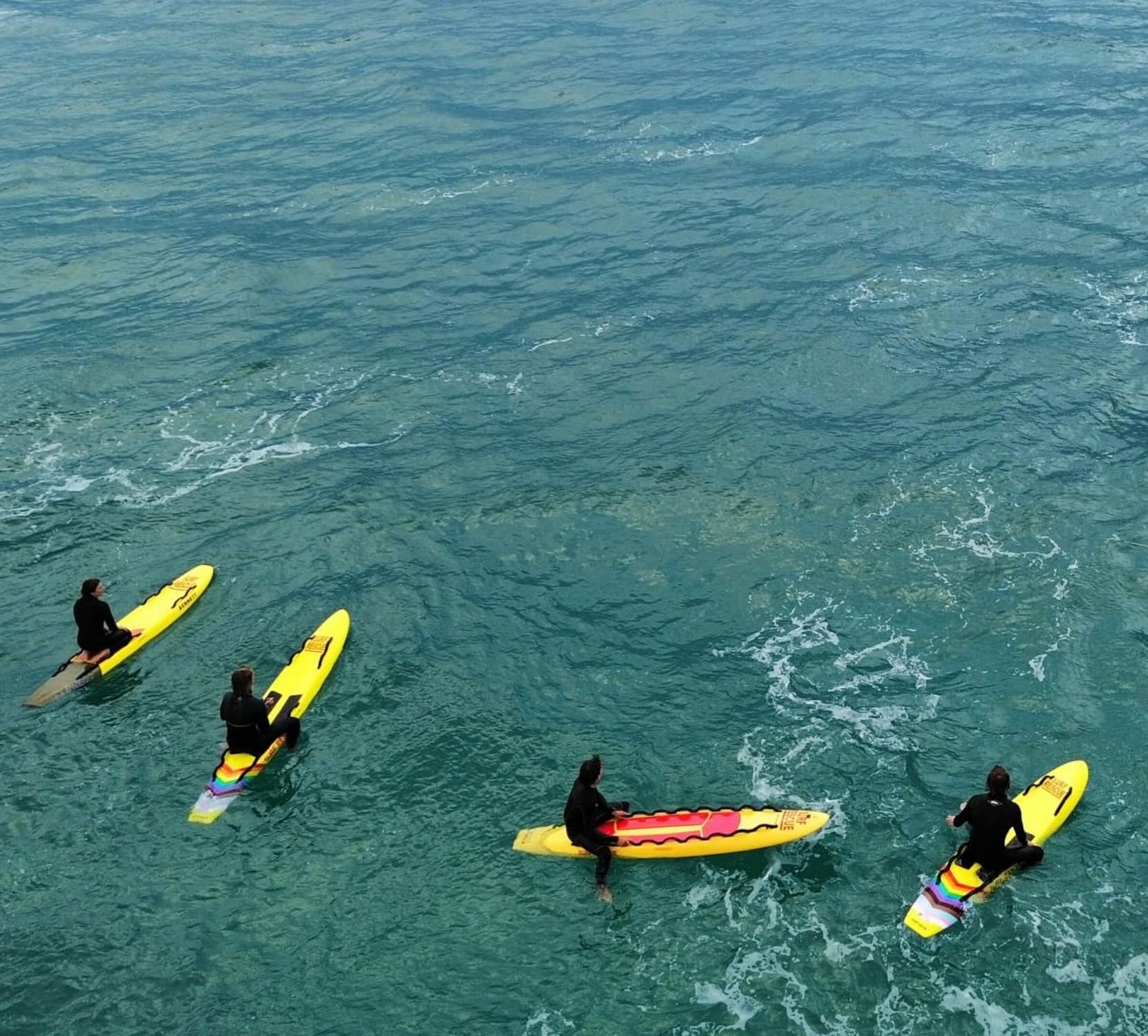 People sitting on rescue boards in the surf